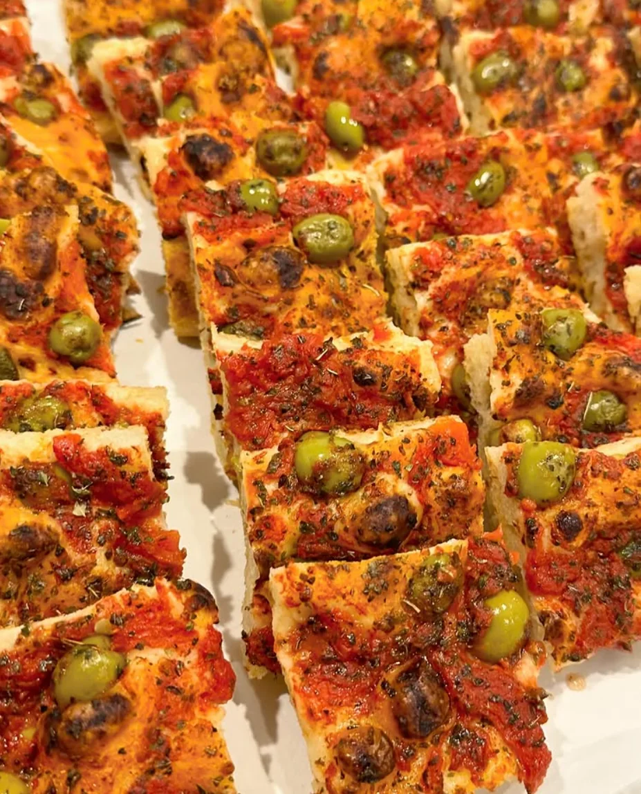 Roman pizza with tomato, olives and herbs cut into slices